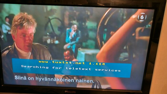 TV-scene med teckensnitt för undertext, texten "Searching for teletext services" och "Siinä on hyvännäköinen nainen". Philips-TV synlig.