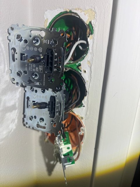 Två dimmers monterade i en vägg, utan täckplattor, med synliga kablar och anslutningar.