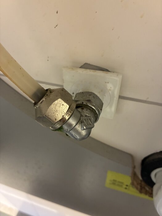 Koppling under tvättställ med gammal blandare, silverfärgad rörkoppling monterad mot vägg. Undersök vilken adapter som behövs.
