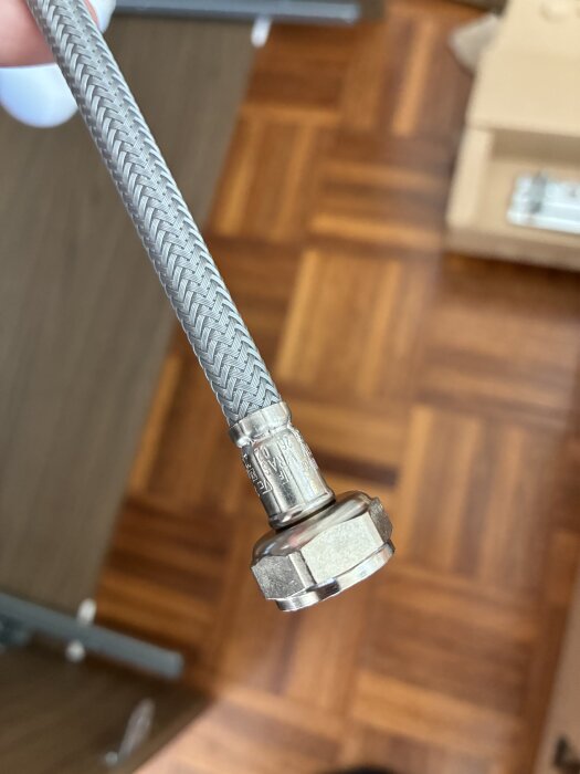 Fleksibel metallslang med en koppling, troligtvis för en tvättställsblandare.
