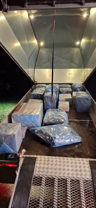 Plastinpackade paket med märkning "Asbest" ligger på släpvagnsflak, redo för transport och deponi.