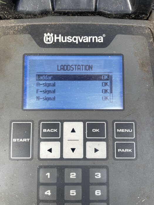 Skärm på Husqvarna laddstation som visar "Laddar OK", "A-signal OK", "F-signal OK", "N-signal OK" samt knappar för navigering.