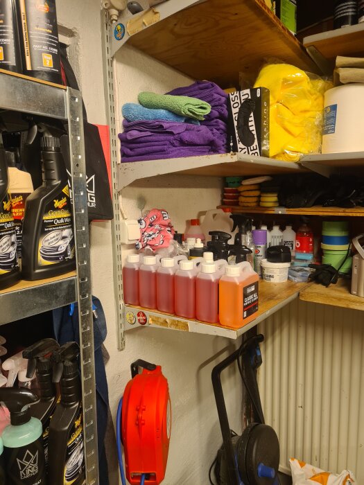 Hyllor med bilvårdsprodukter inklusive flaskor, trasor och rengöringsmedel i ett garage.