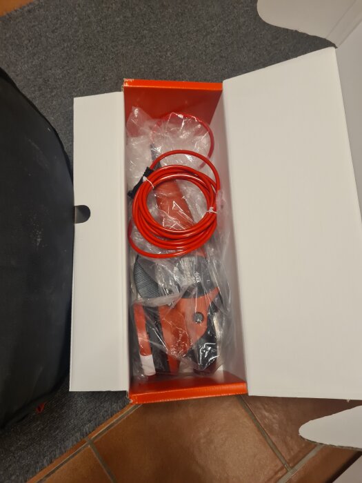 Ny bilvårdsmaskin i kartong, röd kabel synlig.