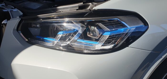 Närbild på strålkastaren på en grå BMW med laserljus, visar detaljer av bilens lack och lampdesign efter keramisk lackförsegling.