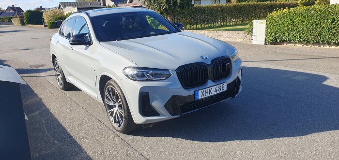 Vit BMW SUV parkerad på gata i bostadsområde, soligt väder.