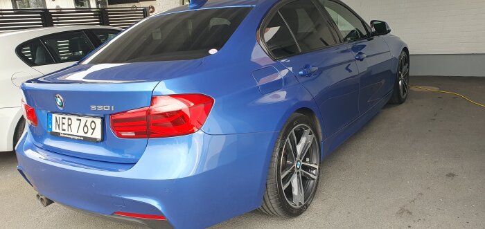 Blå BMW 330i parkerad i ett garage, sett bakifrån med registret NER 769. Rentvättad för hand enligt forumdeltagarens kommentar.