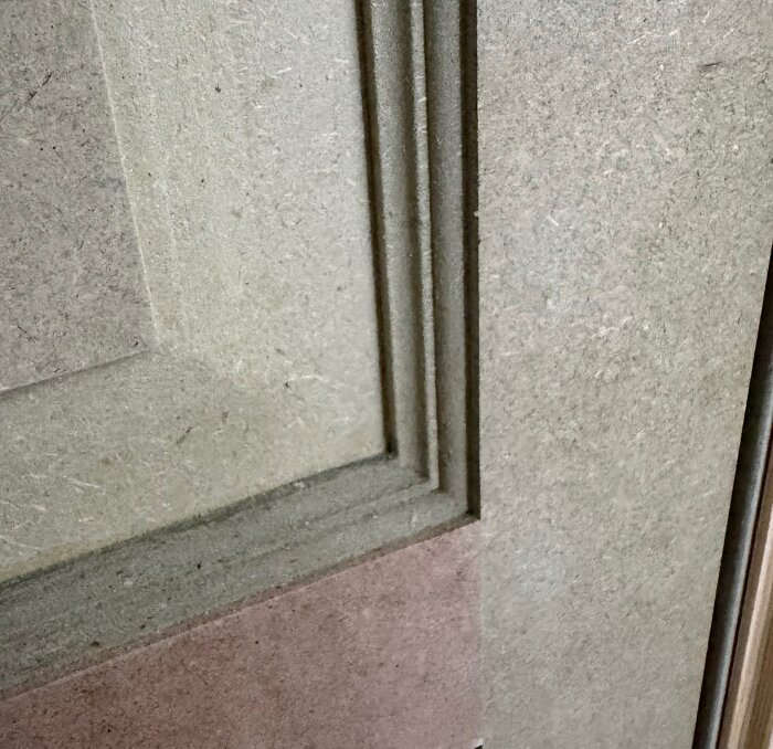 Närbild av MDF-skiva med frästa klassiska profiler som visar struktur och täthet i materialet.