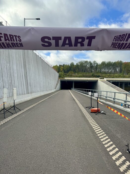 Tunnelöppning vid vägarbete med startlinje och skyltar.