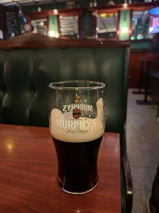 Ett glas mörk öl märkt Murphys på ett träbord i en pubmiljö.