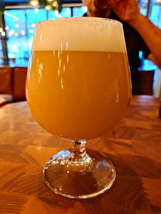 Ölglas på ett bord, fyllt med skummig Omnipollo Dream Baby Dream-öl.