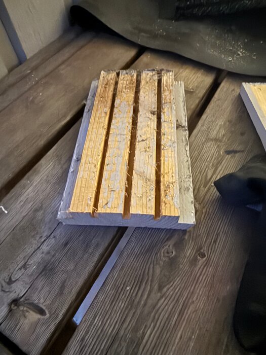 Träplankor med urgröpningar på en arbetsbänk, troligen del av ett byggnadsprojekt.