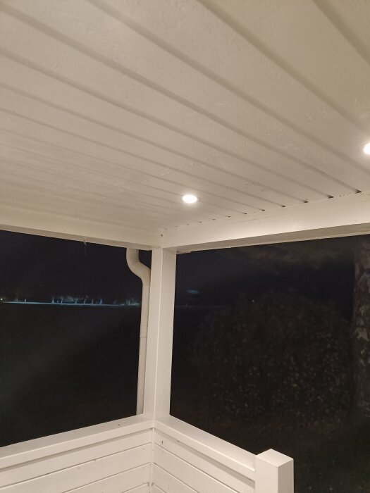 Spotlights installerade i ett vitt tak på en altan, tända på kvällen och nästan osynliga tack vare sin diskreta placering.