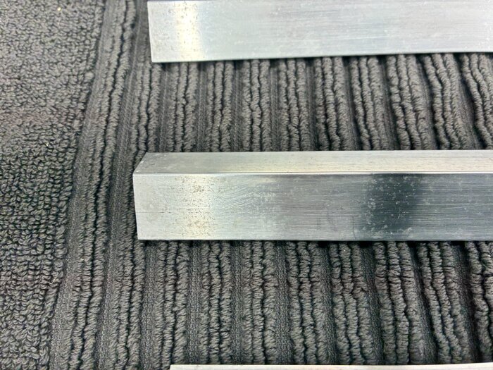 Aluminiumlister från SP fönster med vita prickar på ytan ligger på en mörk yta.