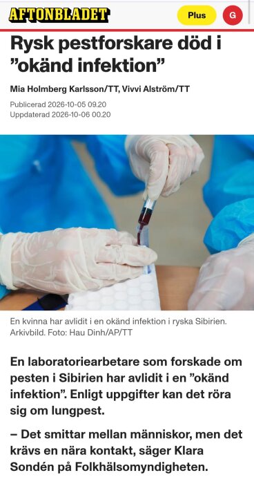 Laboratoriearbetare i blå skyddsdräkt hanterar blodprov med spruta.