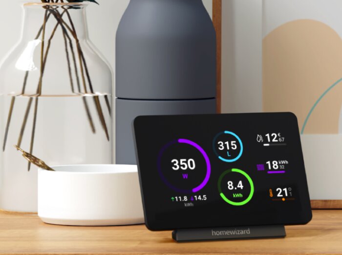 Homewizard display som visar aktuellt energiförbrukning, priser och energimängd. Displayen står på ett bord bredvid dekorföremål.
