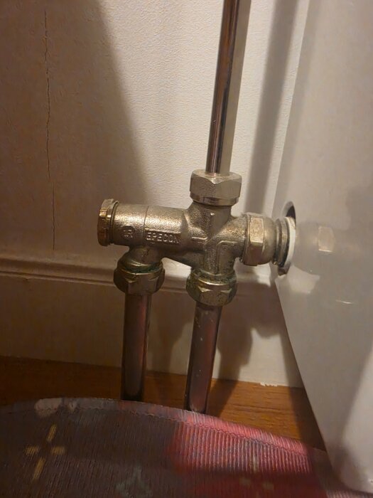 Värmerör- och strypventilinstallation i en vägg, sett ovanifrån, del av en värmesystemjustering.