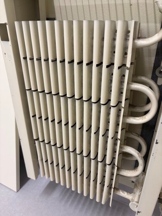 En radiator med avtagbar front som visar en rörslinga med lameller, troligtvis en konvektorbandsradiator från Finland, 1980-talet.