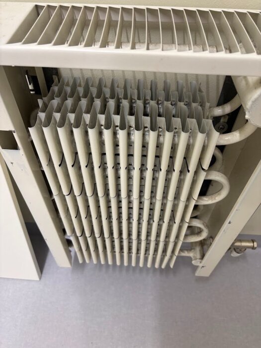 Radiator med borttagen front som visar rörslinga med lameller, troligen en äldre konvektorbandsradiator, vanlig i Finland på 80-talet.