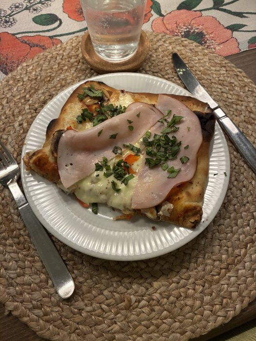 Pinsa med pizzasås, svamp, rödlök, mozzarella, paprika, prosciutto och basilika på en vit tallrik.