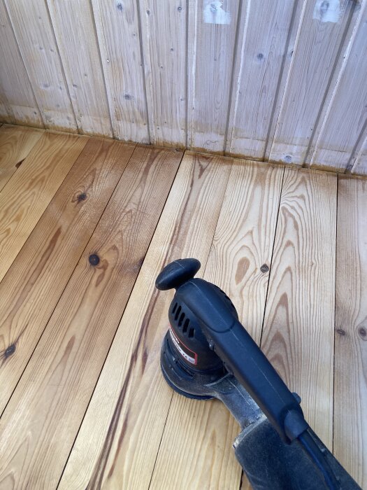 Slipad trägolv med slipmaskin på ytan, halvvägs från lackat till obehandlat.