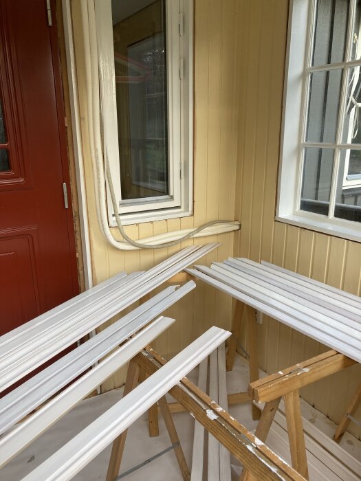 Fönsternisch med järnoxidgula väggar målad i linoljefärg och linoljepolerat golv, tillsammans med vitmålade brädor på bockar.