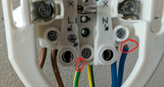 Anslutningsplint med kablar, där bruna, gröna och blå ledare visas. Delvis avskalad blå kabel markerad med röd cirkel.