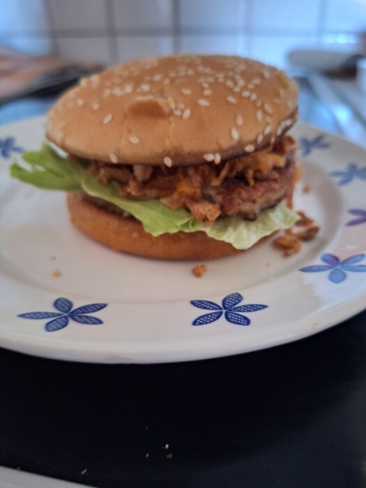Hemlagad hamburgare med sallad och biff på en tallrik med blommönster.