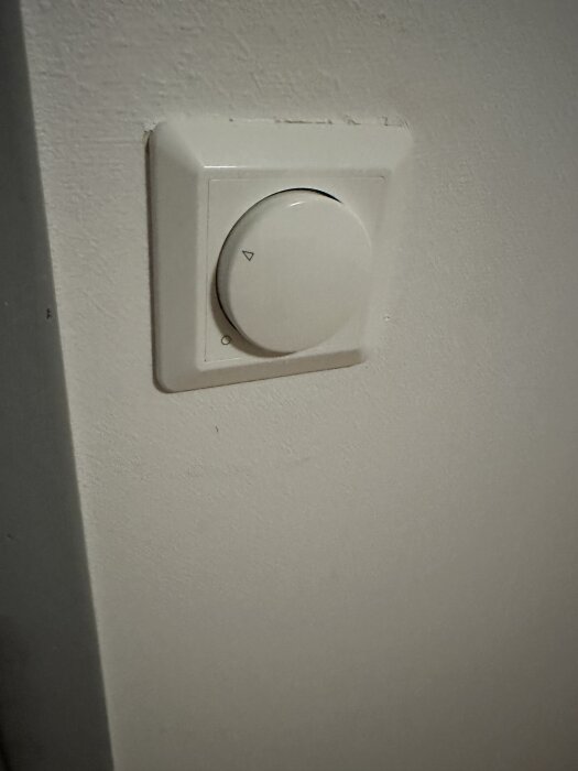 Vred för dimmerbelysning monterat på en vit vägg.