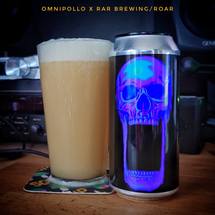 En ölburk med en blå dödskalle på etiketten bredvid ett glas fyllt med öl.
