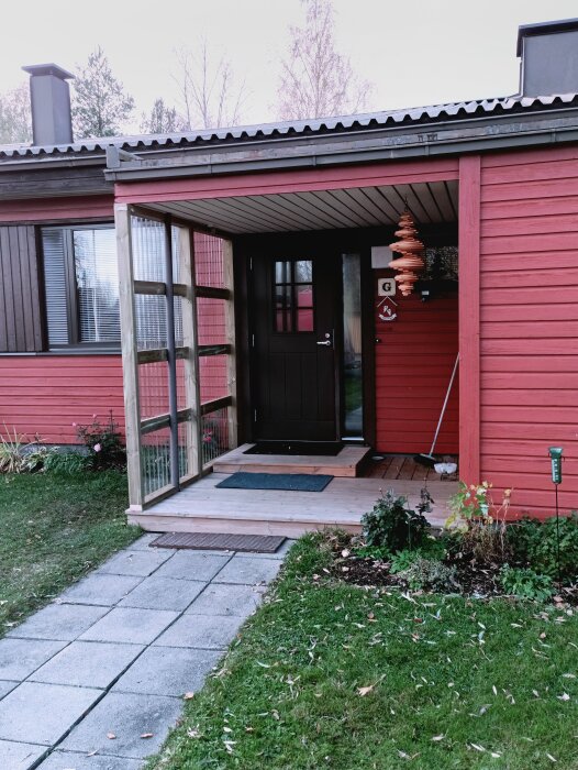 Entré med skydd av impregnerad 2x4 och 0.8mm polytak, del av ett bygge för att tåla vatten, snö och vind.
