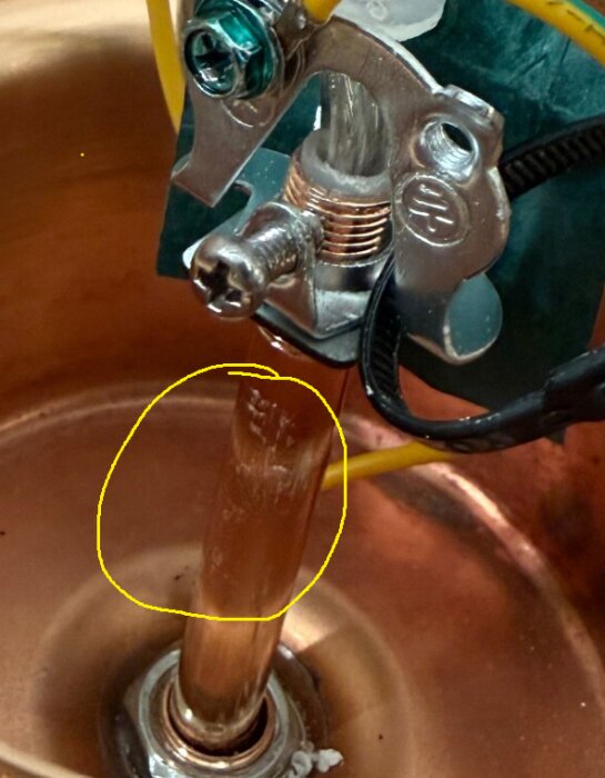 Ledningsanslutning i kopparrör med antydan av tidigare justering markerad i gul cirkel.