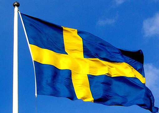 Svenska flaggan vajar mot en blå himmel.