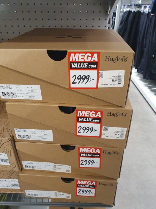 Fyra skokartonger från Haglöfs med prislappar på 2999 kr, staplade på en hylla i en butik.