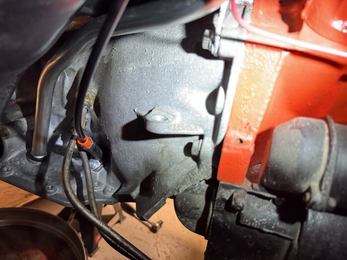 Närbild av en motor med monterat växelvajerkitt och oljesticksrör, delar av motorn och dess komponenter synliga.