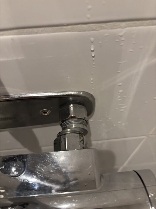 Bild av VVS-koppling med synliga muttrar och kran på en kaklad vägg, frågar om en passande blandare för 160cc väggfäste.
