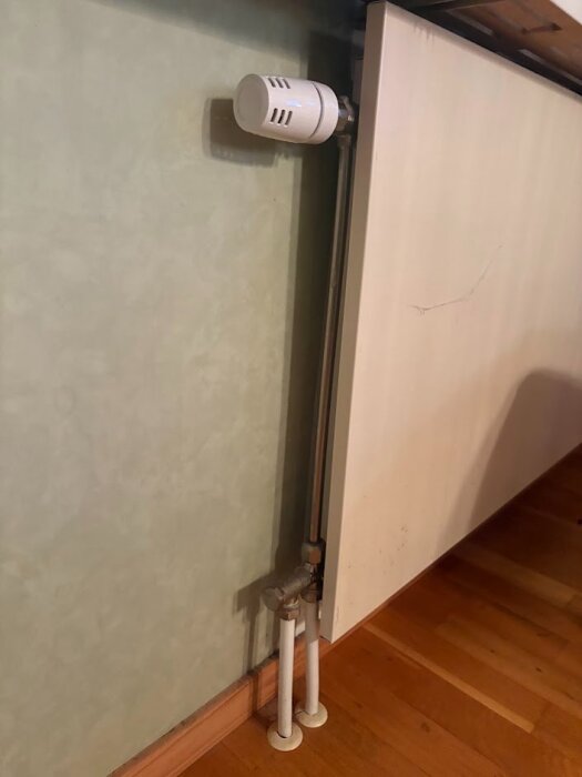 Radiator med två rör, framledning och retur, vid vägg.