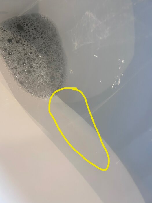 Tömning av vatten med bubblor i badkar, en gul markering visar en specifik punkt på ytan.