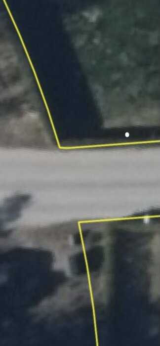 Karta med gulmarkerade tomtgränser och en vit prick som markerar stolpens plats nära en väg i ett bebyggt villaområde.