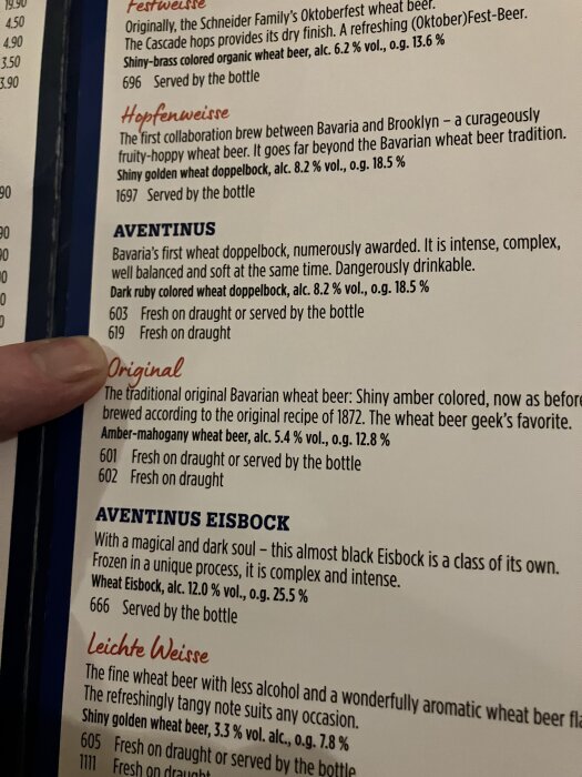 Ölutbud på meny med beskrivningar av Aventinus doppelbock och Original bayerskt veteöl, finger pekar på beskrivningstext.