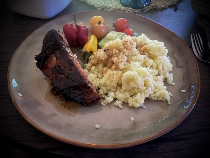 Tallrik med juliga revben, pressad potatis och små färgglada tomater, serverad som en middag.