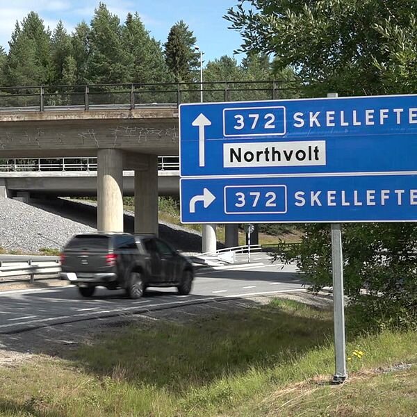 Vägskylt visar vägen till Skellefteå och Northvolt anläggning, med en bil på en väg under en bro omgiven av skogsområde.
