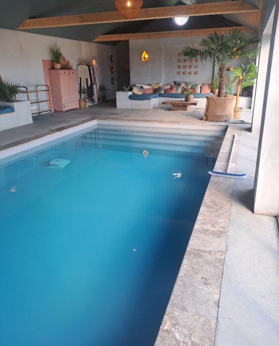 Inomhuspool med modern inredning, väggar i neutrala färger, växter och bekväma sittplatser i bakgrunden.