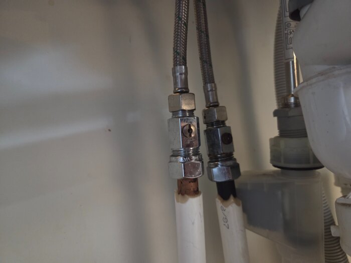 Befintliga VVS-anslutningar under diskbänken med kopparrör och flexibla slangar, kopplade till ballofixer och avloppsrör.