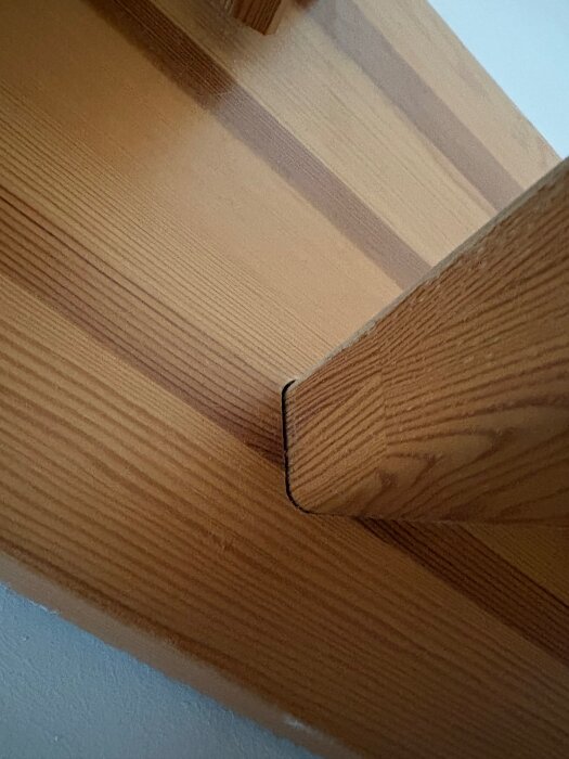 Närbild av trappa där sättsteg delvis glider ur spåret, tydlig trästruktur syns.
