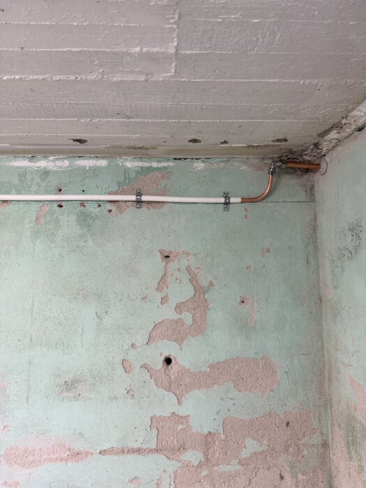 Vattenrör och anslutning på sliten vägg; nyligen installerad för att ge vattenutkastare på framsidan av huset.