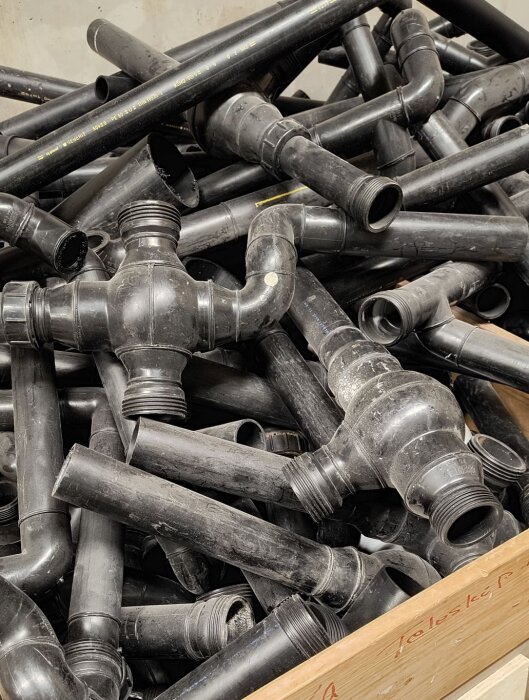 En hög med svarta plast- och metallrör i en källare. Påminner om "pipes" skärmsläckare från gamla NT4-system.