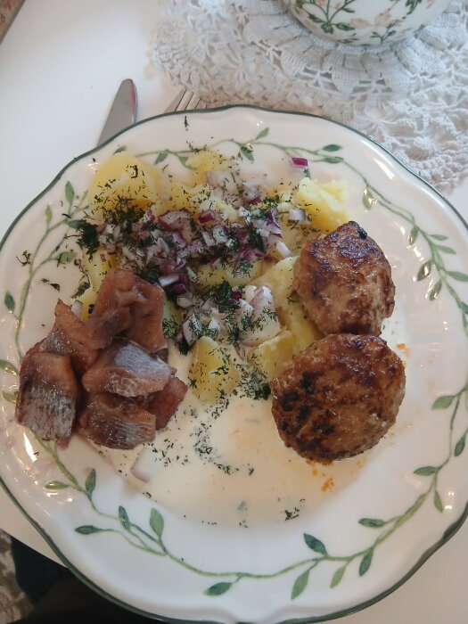 Tallrik med sill, potatis, sås och färsbiffar, garnerad med dill och hackad rödlök.