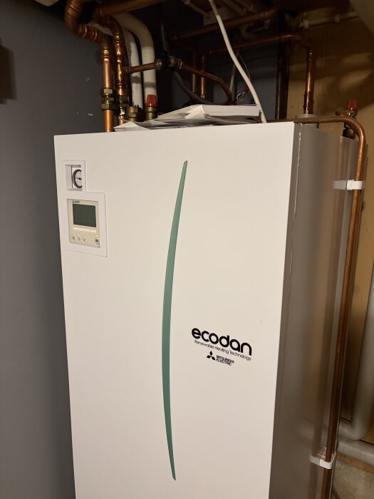 Värmepump med kopparrör ansluten, märkt "ecodan" och installerad i ett tekniskt utrymme.