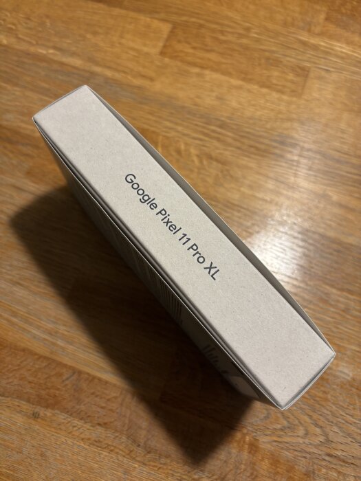 Förpackning av Google Pixel 11 Pro XL på ett trägolv.